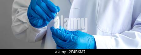 Flasche Impfstoff in der Hand der Forscher. Coronavirus Disease 2019 Testverfahren in einem Labor. Nahaufnahme Stockfoto
