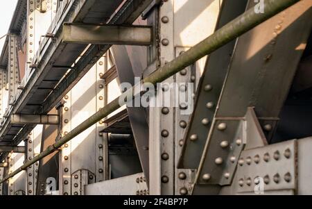 Schienenbrücke, Detail auf Stahlplatten, Gelenke, große Muttern und Schrauben von der Sonne beleuchtet. Abstrakter industrieller Hintergrund Stockfoto