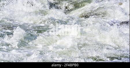 Schnelle Quelle Fluss über Felsen an sonnigen Tag, bilden weiße Wasserwellen, Nahaufnahme Detail - abstrakte Natur Hintergrund Stockfoto