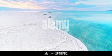 Morgensonne scheint auf Salzkristallen Formationen, klares cyangrünes ruhiges Wasser in der Nähe, typische Landschaft am ein Bokek Strand, Israel Stockfoto