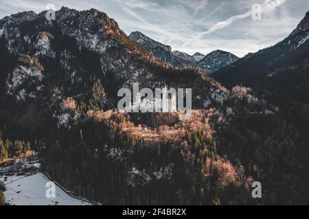 Luftdrohnenaufnahme des malerischen Schlosses Neuschwanstein auf einem verschneiten Hügel Im Winter Sonnenlicht in Deutschland Stockfoto