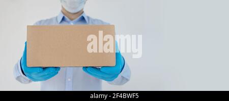 Delivery Mann hält Kartons in medizinischen Handschuhen und Schutzmaske auf weißem Hintergrund. Coronavirus. Stockfoto
