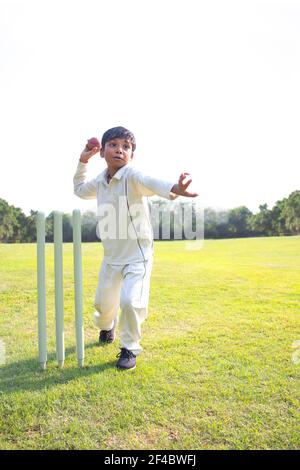 Kleiner Junge Bowling Bein Spin in einem Cricket Stockfoto