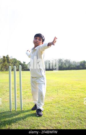 Kleiner Junge Bowling Bein Spin in einem Cricket Stockfoto