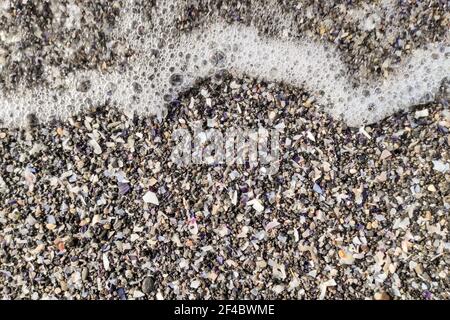 Sanfte Welle am schwarzen vulkanischen Sandstrand. Hintergrund mit Kopierbereich. Stockfoto