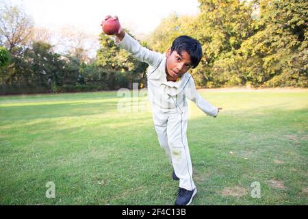 Kleiner Junge Bowling Bein Spin in einem Cricket Stockfoto