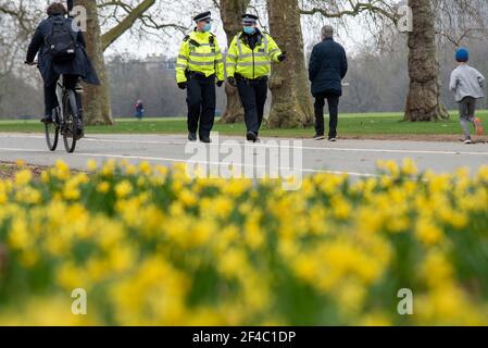 Hyde Park, London, Großbritannien. März 2021, 20th. Eine Reihe von Anti-Lockdown-Protesten sind für Städte auf der ganzen Welt, einschließlich London, geplant. Die Polizei patrouilliert zahlreiche Standorte an wahrscheinlichen Treffpunkten, darunter im Hyde Park, am ersten Frühlingstag in Großbritannien. Narzissen sind draußen im Park, als zwei Polizisten mit Gesichtsmasken gehen Stockfoto