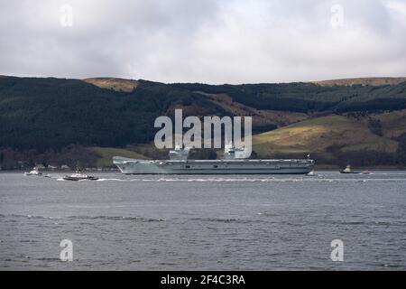 Cove, Argyle und Bute, Schottland, Großbritannien. März 2021, 20th. IM BILD: Schlepper manövrieren HMS Queen Elizabeth, während sie in den Firth of Clyde segelt. Die Leute beobachten, wie die HMS Queen Elizabeth nach fast einer Woche in Loch Long in Glenmallan, wo sie Treibstoff, Munition und andere Vorräte annahm, vor den Marineübungen, die Teil der britischen Carrier Strike Group 2021 sind, die Segel setzte. Quelle: Colin Fisher/Alamy Live News Stockfoto