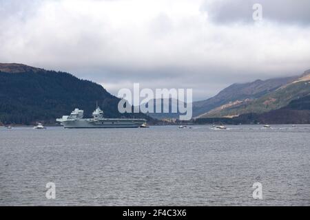 Cove, Argyle und Bute, Schottland, Großbritannien. März 2021, 20th. IM BILD: Die Leute schauen, wie die HMS Queen Elizabeth nach fast einer Woche in Loch Long in Glenmallan, wo sie Treibstoff, Munition und andere Vorräte annahm, vor den Marineübungen, die Teil der britischen Carrier Strike Group 2021 sind, die Segel setzte. Quelle: Colin Fisher/Alamy Live News Stockfoto