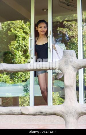 Eine junge Frau öffnet die Tür auf der Veranda und Sieht aus Stockfoto