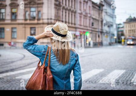 Frau in der Stadt verloren. Schöner junger Tourist, der auf der Straße läuft. Frau trägt Jeans-Hemd und Strohhut. Stockfoto