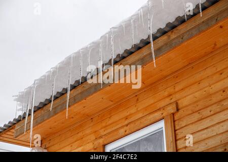 Frühling Eiszapfen auf dem Dach des Hauses. Muster von Sonne und Frost verstreut. Selektiver Fokus Stockfoto