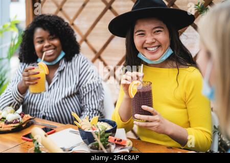 Multirassische Freunde, die gesundes Mittagessen trinken Obst frische Smoothies in Kaffee Brunch Bar während Corona Virus Ausbruch Stockfoto