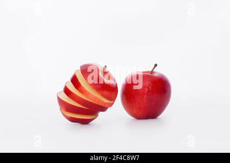 Lecker aussehende Apfelscheiben neben einem ganzen Apfel auf einem hellen Hintergrund. Selektiver Fokus und Nahaufnahme. Gesunde Ernährung und abstraktes Konzept. Stockfoto