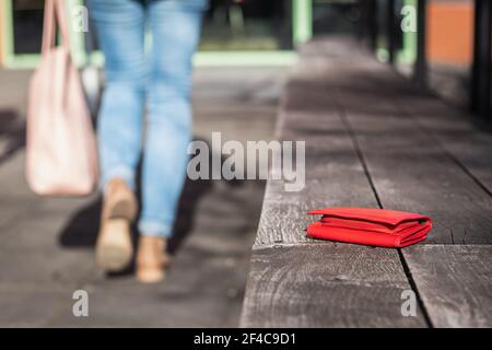 Geldbörse auf der City Street verloren. Frau verlässt eine Bank, wo sie ihre Ledertasche vergessen hat Stockfoto