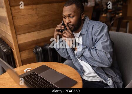Nahaufnahme Porträt des Unternehmens afroamerikanischen jungen Mann auf Handy im Büro sprechen. Er bittet um Ruhe, er hat eine sehr wichtige Sache Stockfoto