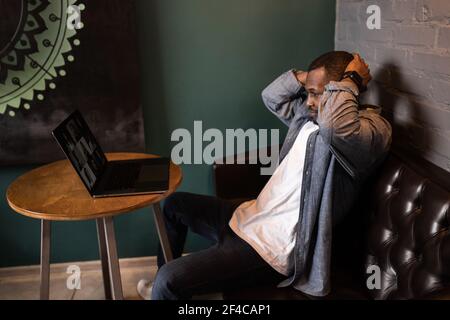 Frustrierter afrikanischer Geschäftsmann, der an der Rezeption saß und seinen Kopf hielt und schlechte, schreckliche negative Nachrichten las, die von der Arbeit entlassen wurden. Kündigungsmitteilung, finanzielles Problem Stockfoto