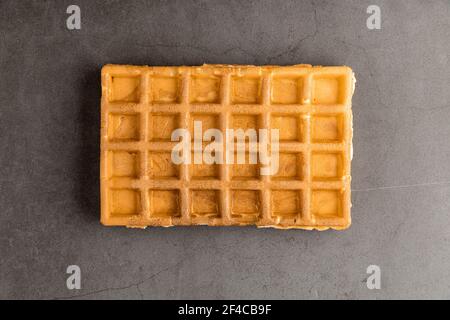 Einzelne belgische Waffel auf dunklem Steingrund. Stockfoto