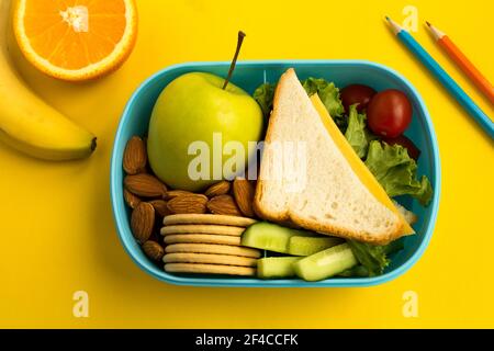 Schulessen in der Box auf dem gelben Hintergrund.Draufsicht. Stockfoto