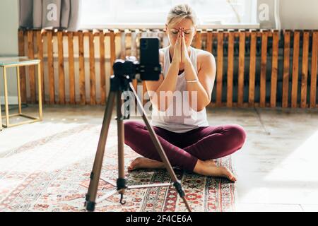 Eine Yogi-Frau zeichnet eine Meditationsstunde auf einer Handykamera auf. Stockfoto