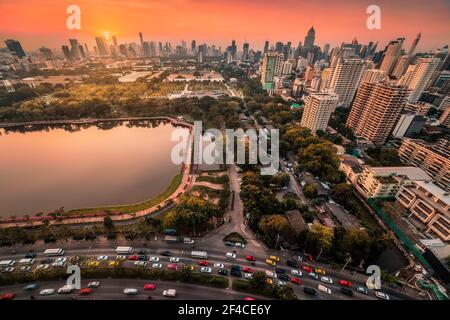 Benjakiti Public Park mit einem See, Wolkenkratzer und Verkehr in Bangkok, Thailand bei Sonnenuntergang Stockfoto