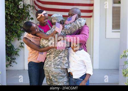 afroamerikanischer Soldat Vater umarmt Frau, Kinder und Vater vor dem Haus Stockfoto