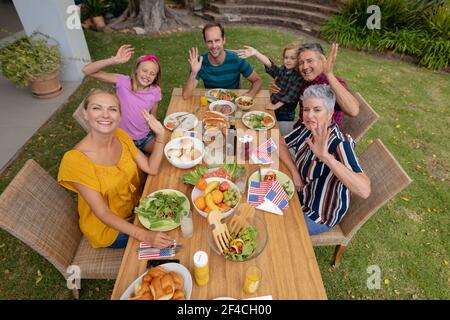Kaukasische drei Generation Familie mit Feier Mahlzeit im Garten lächelnd Und winken zur Kamera Stockfoto