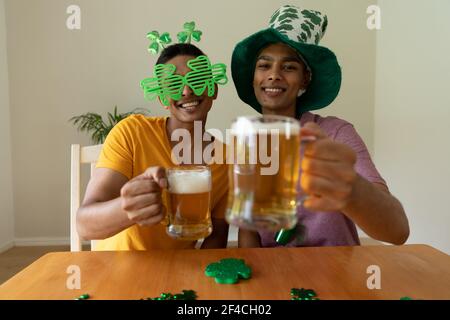 Porträt von verschiedenen Homosexuell männlichen Paar trägt st patrick's Tag Kostüme und mit Gläsern Bier Stockfoto