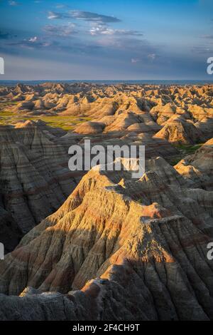 Sonnenaufgangslicht regt die erodierten Zinnen und Schluchten bei Big Badlands Overlook im Badlands National Park, South Dakota. Stockfoto