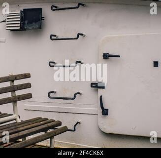 Sitzen vor einer metallenen Schiffswand mit Stufen Und Hatchway Stockfoto