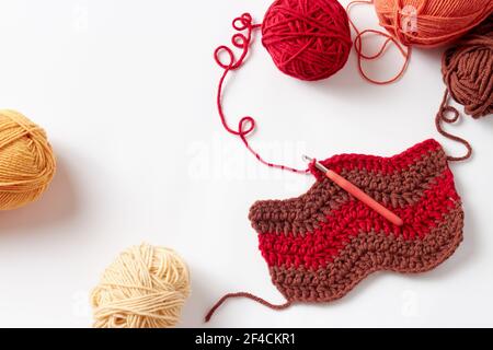 Buntes Häkelprojekt mit Haken und Garn, auf weißem Hintergrund. Stockfoto