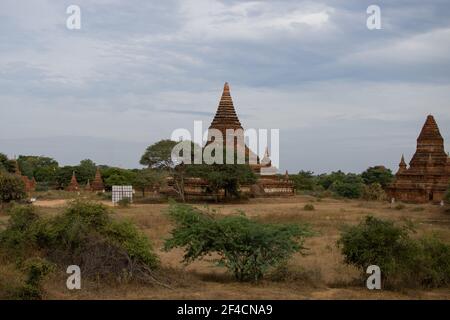 BAGAN, NYAUNG-U, MYANMAR - 3. JANUAR 2020: Alte und historische Pagodentempel, umgeben von grüner Vegetation an einem heißen Tag Stockfoto