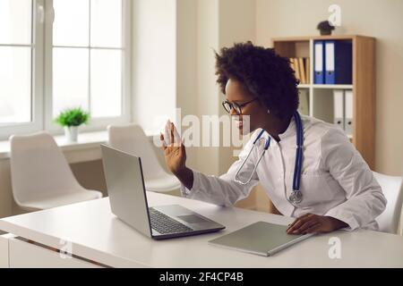 Die junge dunkelhäutige Ärztin bietet dem Patienten eine Online-Konsultation per Video-Link an. Stockfoto