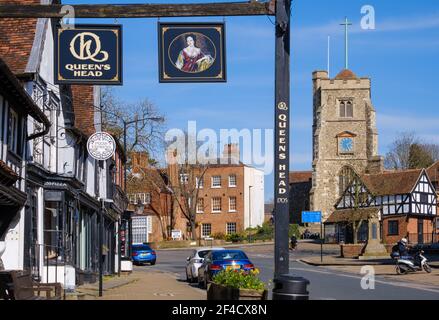 Pinner Village High Street. Historisches Queen's Head Pub & Pizza Express auf der linken Seite & Saint John the Baptist, mittelalterliche Kirche auf einem Hügel im Hintergrund. Stockfoto