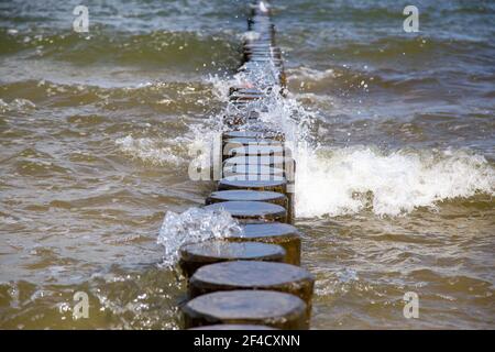 Im Sommer brechen die Wellen auf den Holzplanken an der Ostsee. Stockfoto
