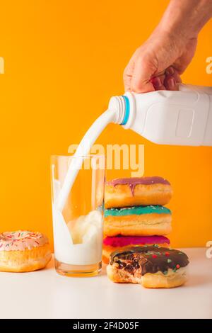 Süße Donuts mit Mann Hand Gießen Milch Stockfoto