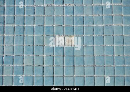 Zwei Löcher zusammen auf dem leeren Poolboden. Steinzeug Swimmingpool Boden, in dem zwei blaue Fliesen fehlen. Stockfoto