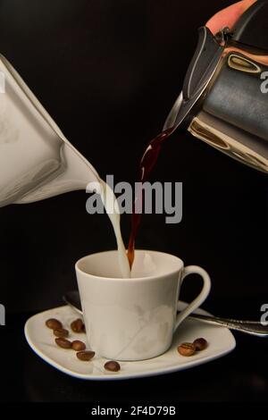 Kaffee und Milch in eine Tasse gießen Stockfoto