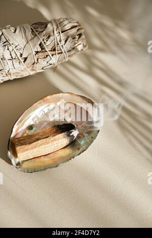 Der beleuchtete Palo Santo-Stick raucht auf einer Schale. Natürliche aromatische Sticks für Heilung, Heilung von Krankheiten, Entspannung, Reinigung Raum von negativen Energie. Stockfoto