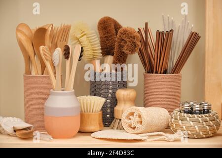 Sammlung von ökologischen Haushaltswaren. Bambuslöffel, Gabeln und Zahnbürsten. Umweltfreundliche Kokos-Spülbürsten, runde Holzspülmaschinen Stockfoto