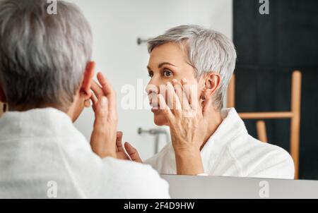 Nahaufnahme der reifen Frau Anwendung Creme mit der Hand Stockfoto