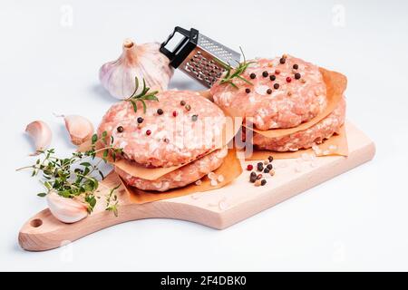 Roher Hähnchenburger auf einem weißen Teller in einem Rosmarinzweig und Gewürze. Fleisch sofort. Gegrillte Hamburger.Raw Hamburger, Fleischbällchen auf weißem Hintergrund.FAS Stockfoto