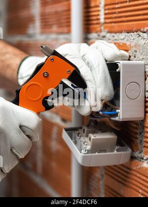 Elektriker Arbeiter bei der Arbeit mit Abisolierer bereitet die elektrischen Kabel der häuslichen elektrischen Anlage. Bauindustrie. Stockfoto