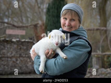 Roskow, Deutschland. März 2021, 15th. Die Bäuerin Katja Behling vom Skuddenhof in Weseram hält Danika, ein Lamm, das am 7. März 2021 geboren wurde, in den Armen. Zusammen mit ihrem Mann betreibt die gelernte Handelsverkäuferin die Zucht von Skudden auf dem Hof, der kleinsten einheimischen Schafrasse, die zu den ältesten Hausschafrassen gehört und weiße Mischwolle produziert. Die Skudde ist auf der Roten Liste der gefährdeten Tierrassen. Quelle: Soeren Stache/dpa-Zentralbild/ZB/dpa/Alamy Live News Stockfoto