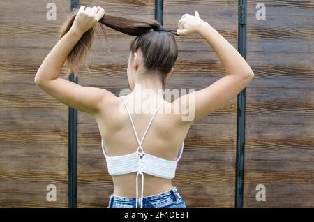 Rückansicht eines Teenagers, das im Freien steht und sie stellt Haare in einem Pferdeschwanz Stockfoto