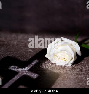 Komposition mit schönen weißen Rose und Schatten des Kreuzes auf rustikalem Hintergrund. Copy space. Stockfoto
