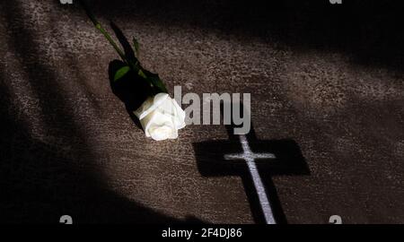 Komposition mit schönen weißen Rose und Schatten des Kreuzes auf rustikalem Hintergrund. Copy space. Stockfoto