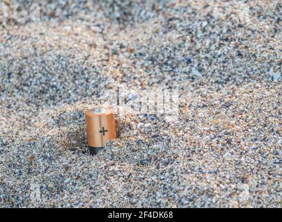 Unsachgemäß entsorgt Batterien im Sand am Strand.Altbatterien. Konzept der Umweltverschmutzung. Stockfoto