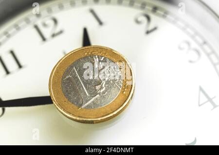 Zeit ist Geldhintergrund mit Wecker und einer Euro-Münze darauf, Nahaufnahme Foto Stockfoto