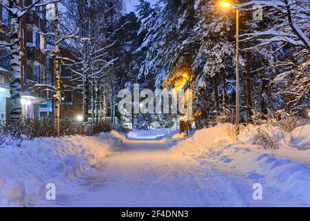 Schneebedeckte Fußgängerstraße im Wohnviertel nach einem Schneesturm am Morgen oder Abend in Finnland. Stockfoto